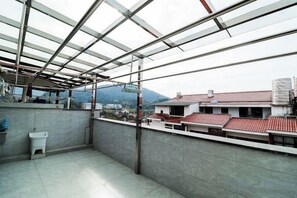 A balcony with a view of buildings and mountains, a sink, and a tiled floor. - Mingyu Shanshe Hostel (Wuyishan)