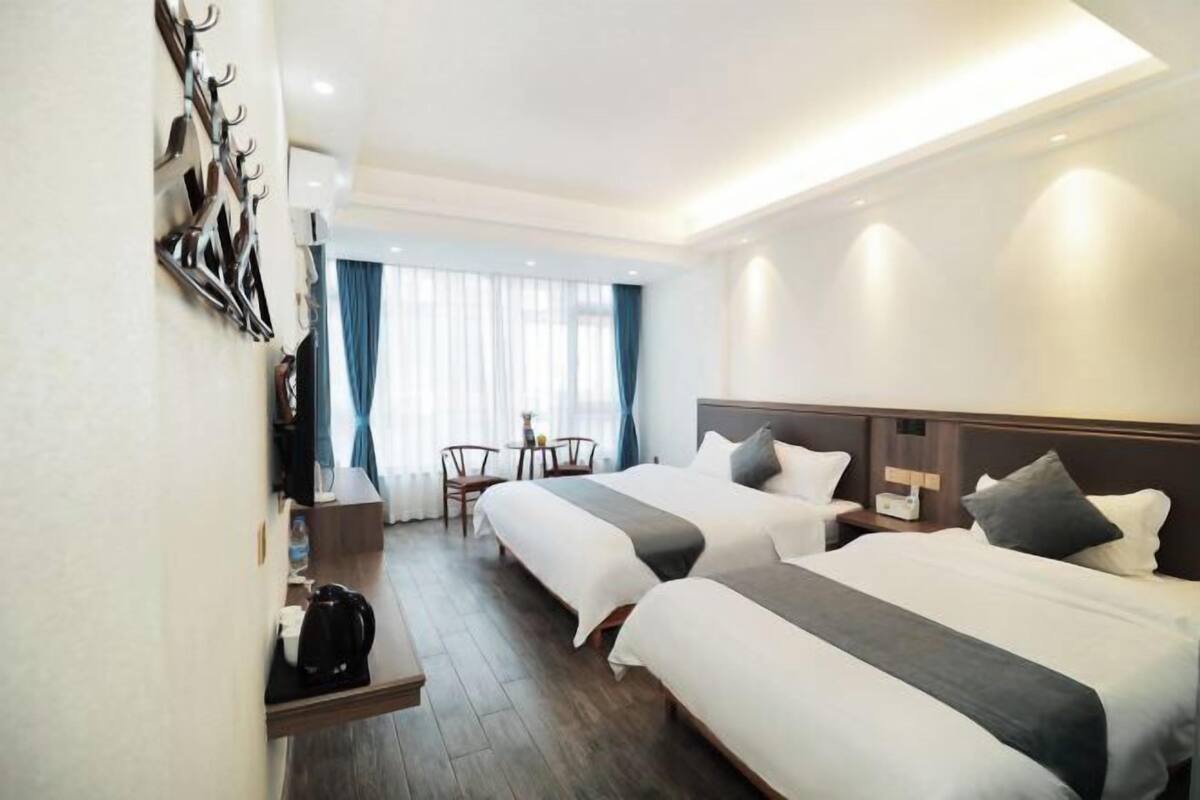 A hotel room with two beds, a coffee maker, a desk, and a chair.