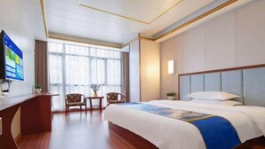 Een hotelkamer met een bed, een bureau, een stoel en een televisie.