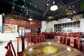 A restaurant interior with round tables, red chairs, hanging plants, and brick walls. - Furong Lijing Hotel (Yongshun)