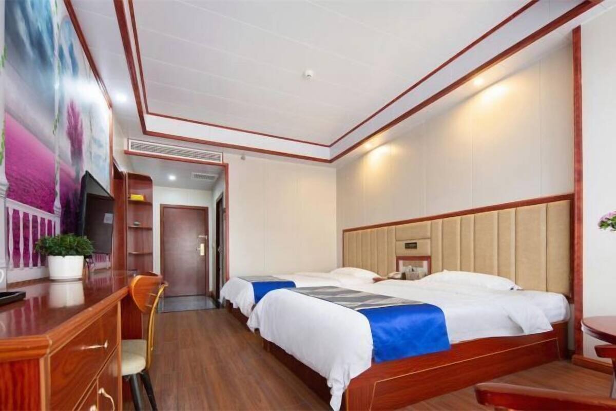 A hotel room with a wooden bed, a desk, a chair, and a television.