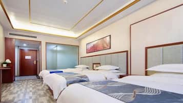 A hotel room with three beds, a door, a painting, and a small table.