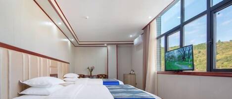 A hotel room with a large bed, a television, and a window with a view of greenery.
