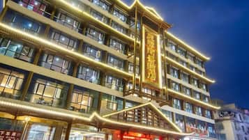 A multi-story hotel with illuminated signage and a traditional architectural design.