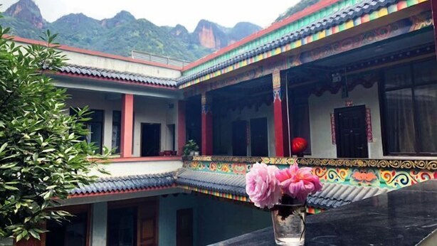 A traditional building with a courtyard, a flower vase, and a mountainous backdrop.