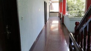 Um corredor comprido e estreito, com uma escada de madeira à direita.