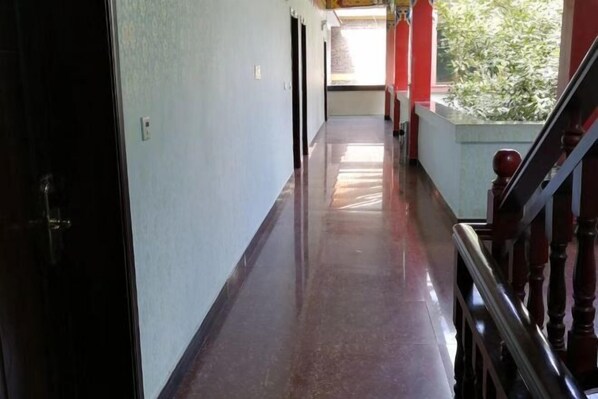 A long, narrow hallway with a wooden staircase on the right. - Zixin Space Leisure Hotel (Yulong)