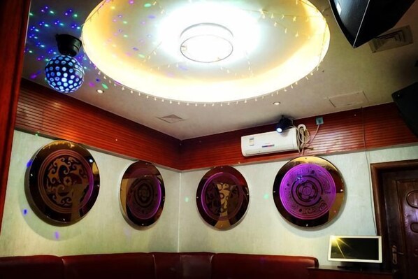 Une pièce dotée d’un luminaire circulaire au plafond, d’un appareil de climatisation et d’assiettes décoratives accrochées au mur.