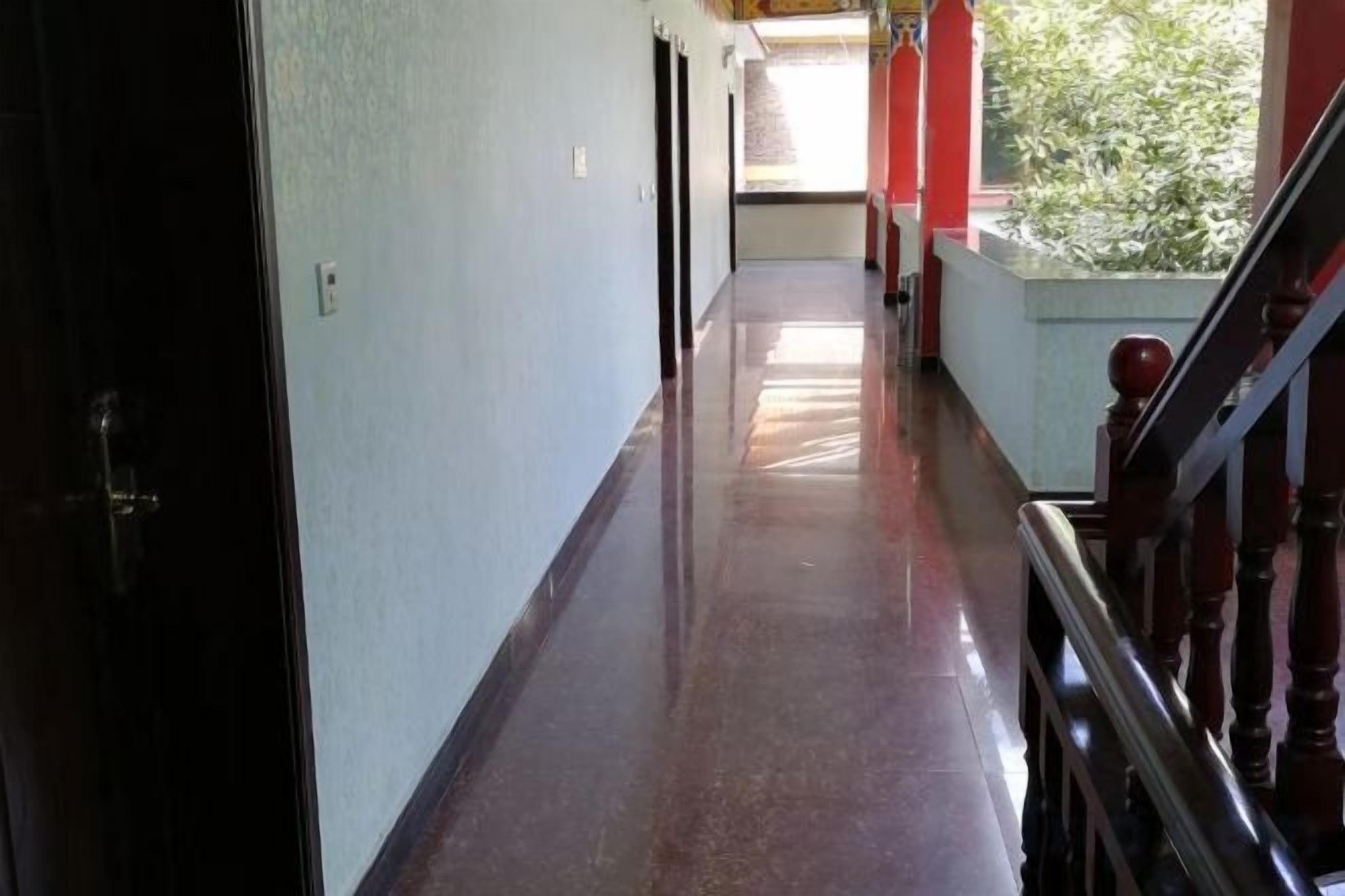 Un couloir doté d’un plancher ciré, d’une rambarde en bois et d’une porte située sur le côté gauche.