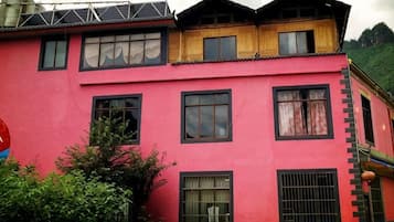 Un immeuble à plusieurs étages, doté d’une façade rouge, de nombreuses fenêtres et d’une toiture au design traditionnel.