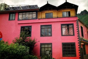 A multi-story building with a red facade, multiple windows, and a traditional roof design. - Zixin Space Leisure Hotel (Yulong)
