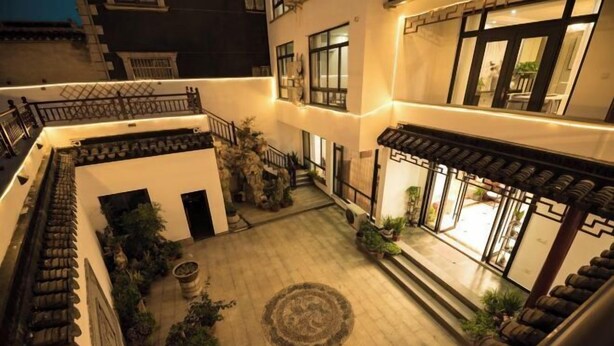 A courtyard with a central circular pattern, surrounding potted plants, and a staircase leading to an upper level. - Sushangyuan Boutique Hostel (Suzhou)