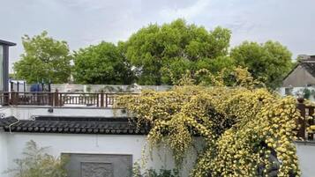 A traditional building with a tiled roof and a tree with yellow flowers in front.