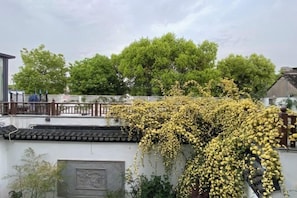 A traditional building with a tiled roof and a tree with yellow flowers in front. - Sushangyuan Boutique Hostel (Suzhou)