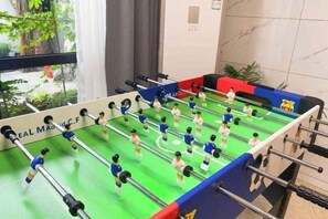 A foosball table in a room with a view of a garden through a window. - Sushangyuan Boutique Hostel (Suzhou)