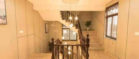 A staircase with a wooden railing and a chandelier.