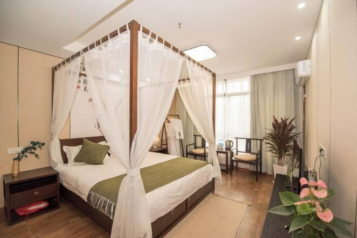 A bedroom with a four-poster bed, bedside tables, a desk, and chairs.