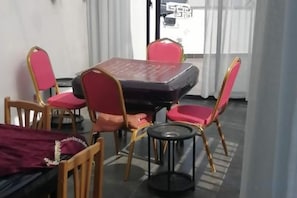 A dining area with a table and chairs, a bed, and a window with curtains. - Sushangyuan Boutique Hostel (Suzhou)