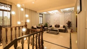 A spacious lobby with a wooden staircase, a seating area with sofas, and a large window providing natural light. - Sushangyuan Boutique Hostel (Suzhou)