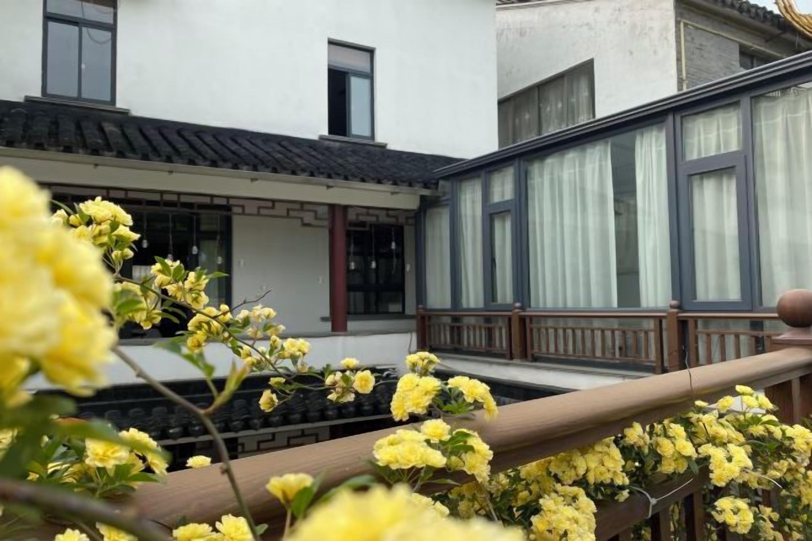 A traditional building with a balcony, a wooden railing, and yellow flowers in the foreground.