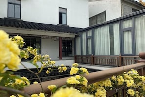 Un edificio tradicional con un balcón, barandilla de madera y flores amarillas en primer plano.