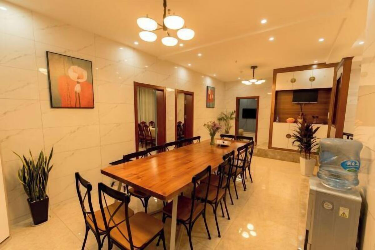 A dining area with a wooden table and chairs, a water dispenser, and a television on the wall.