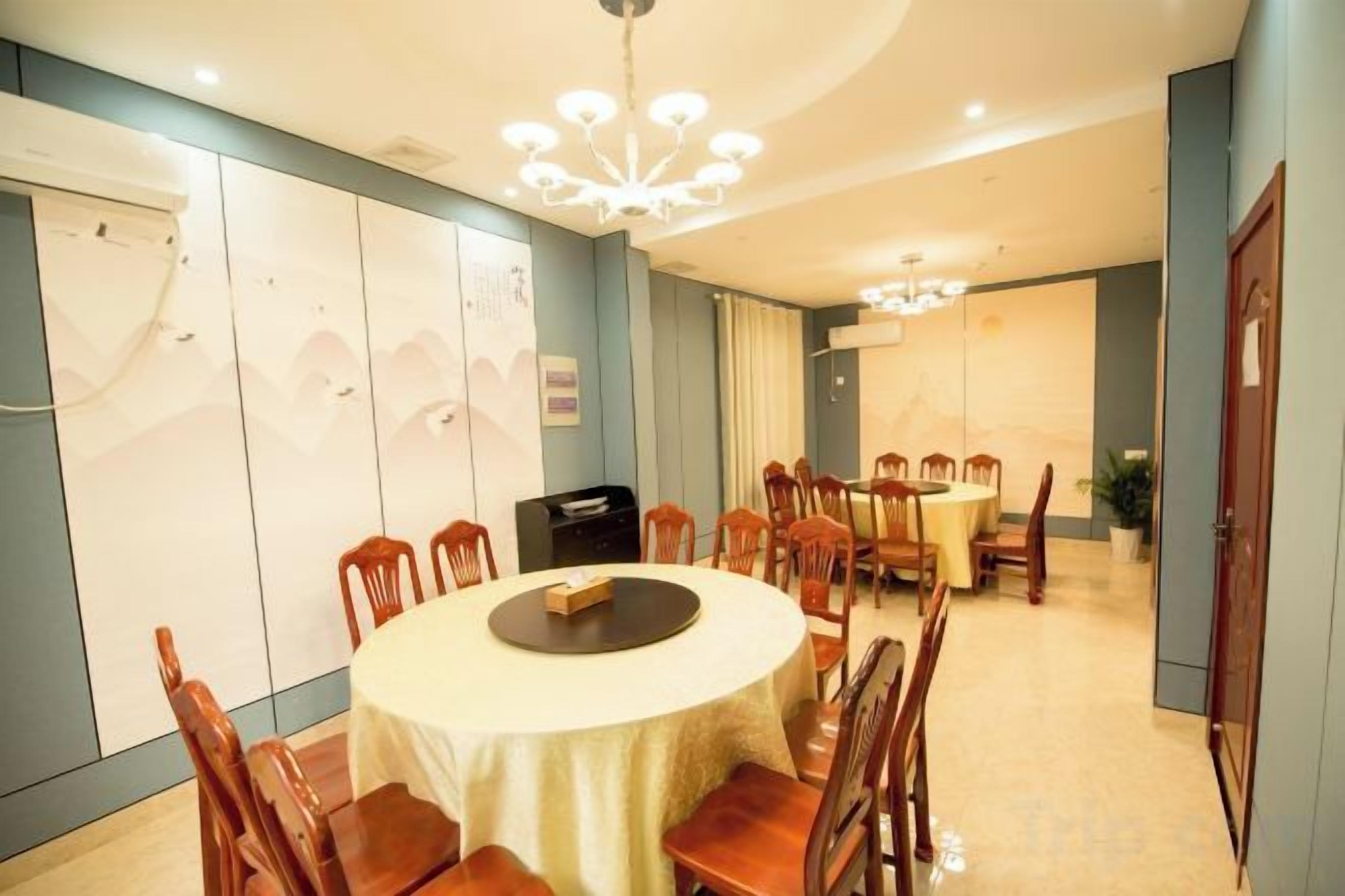 A dining area with a round table, chairs, and a chandelier.