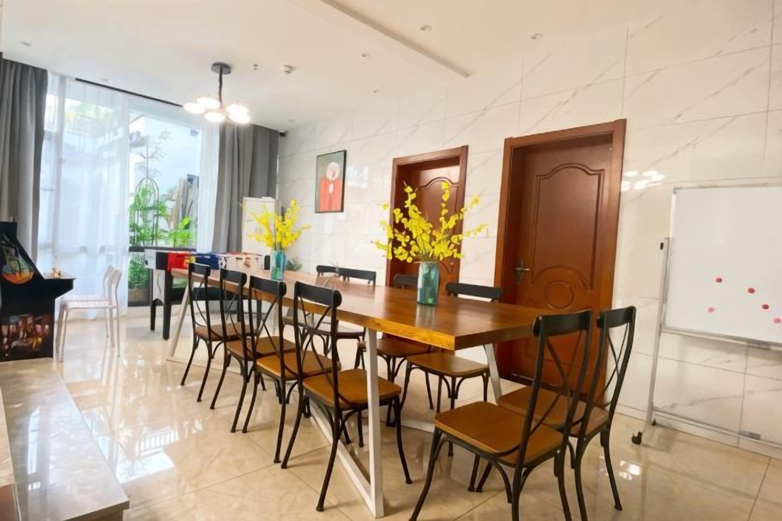 Un área de comedor con una mesa larga, sillas y una pizarra.