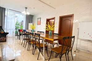 Uma sala de jantar com uma mesa comprida, cadeiras e um quadro branco.