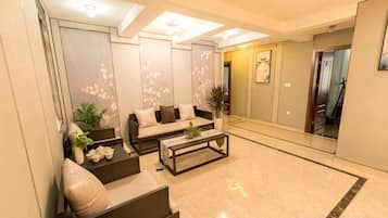 Uma sala de estar moderna com sofá, mesa de centro, cadeiras, um espelho grande e uma planta.