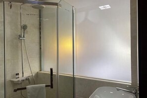 Une salle de bain moderne avec une douche à l’italienne, une baignoire et un porte-serviettes.
