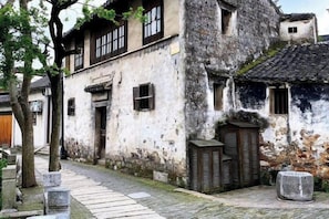 Un edificio tradicional con un camino de piedra, puertas de madera y techo de tejas.