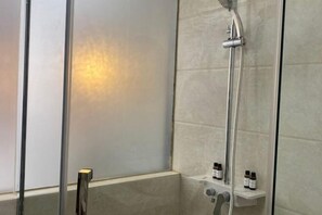 Une salle de bain moderne avec une douche à parois de verre, un meuble-lavabo avec un miroir et une étagère pour les articles de toilette.