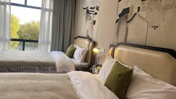 Habitación de hotel con dos camas, un ventanal grande con cortinas y una pared con arte abstracto.