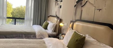 Habitación de hotel con dos camas, un ventanal grande con cortinas y una pared con arte abstracto.