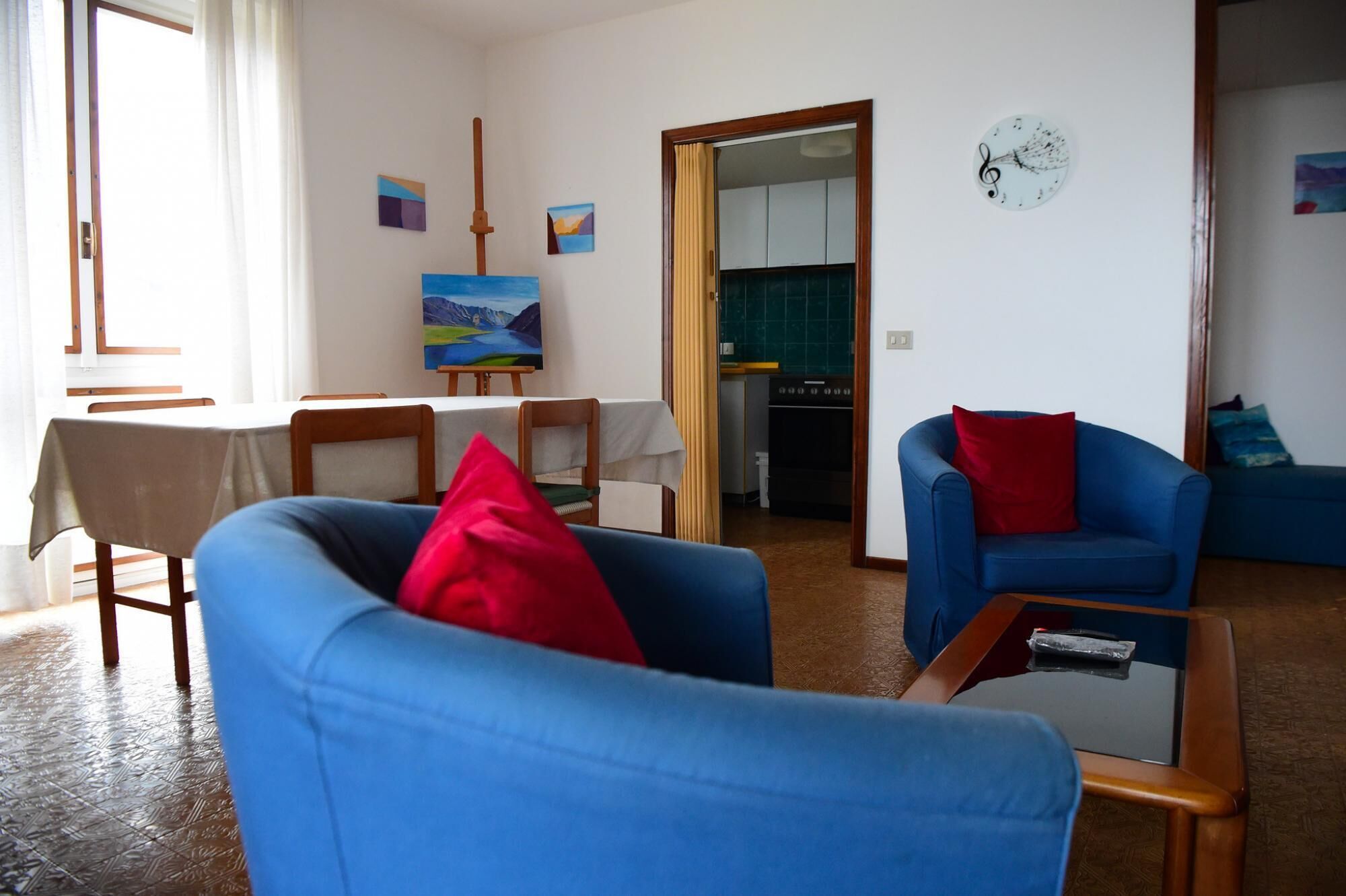 Un salon avec deux fauteuils bleus, une petite table et un tableau accroché au mur.