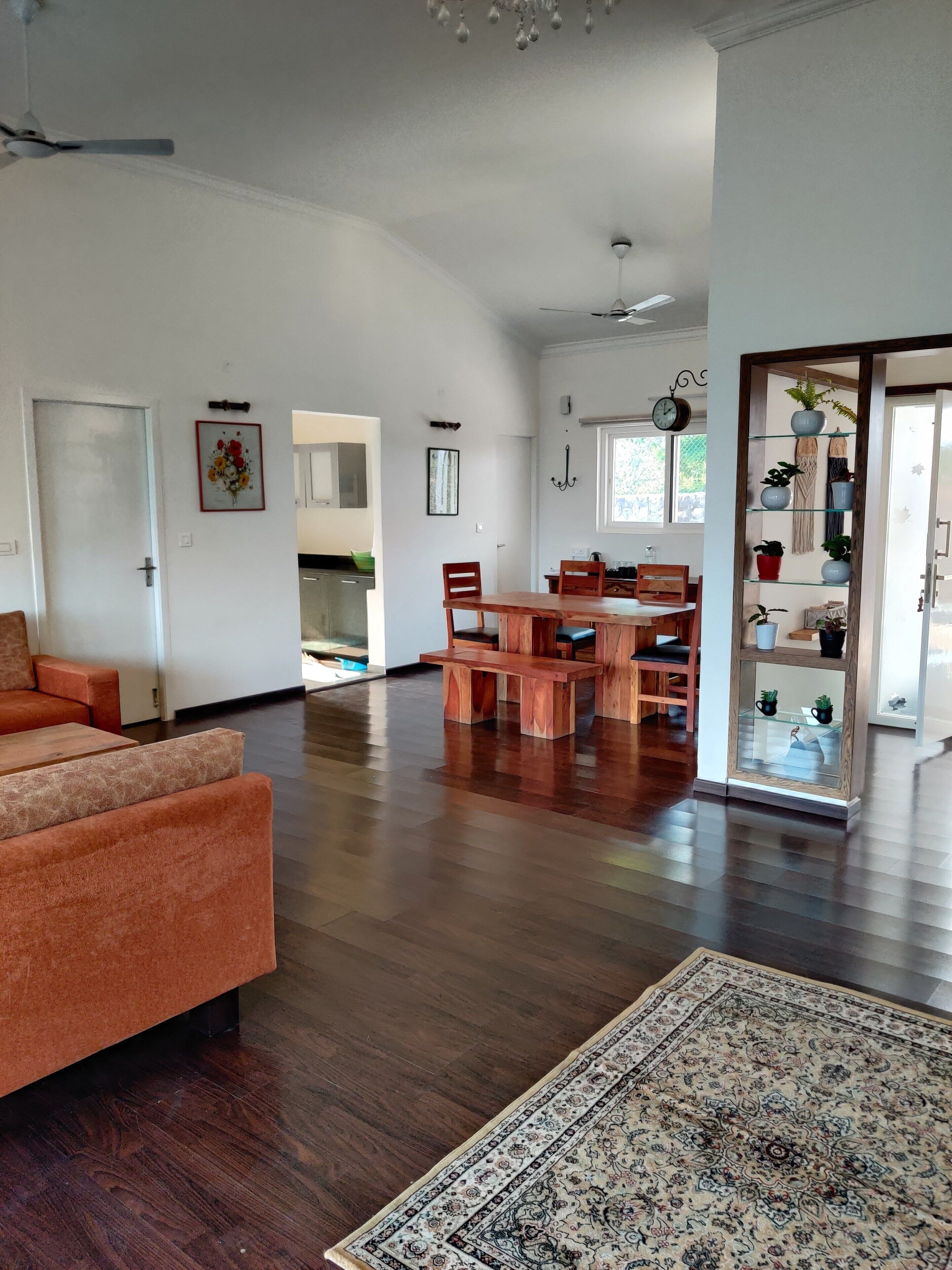 A spacious living area with a wooden floor, a large rug, and a dining table with chairs.