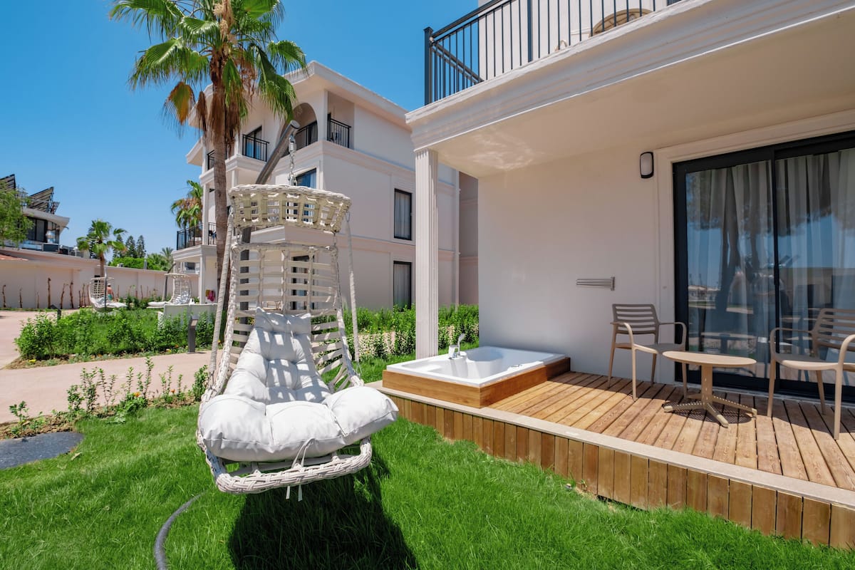 Un espacio exterior moderno con terraza de madera, un jacuzzi y una silla colgante.
