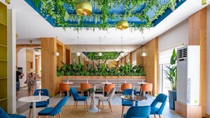 Un espacio interior moderno con suelo de espiga, paneles de madera en las paredes y una zona de estar central con sillas azules y naranjas.