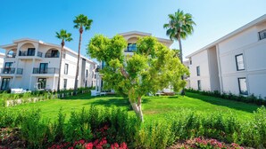 Un hotel moderno con un patio central, palmeras y un jardín bien cuidado.