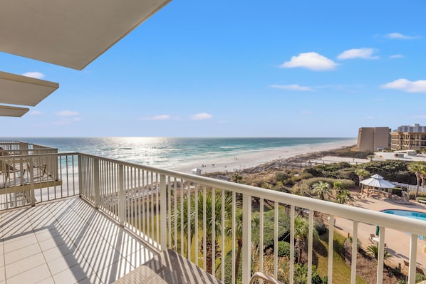 A balcony with a view of the beach and ocean.