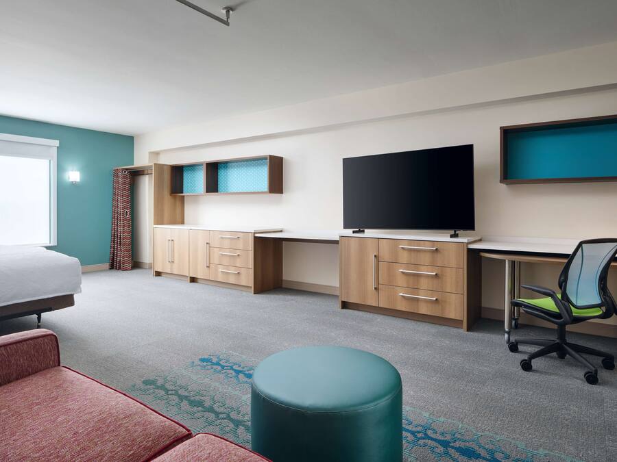 Una camera d'albergo con un letto, una scrivania, una televisione e una sedia.