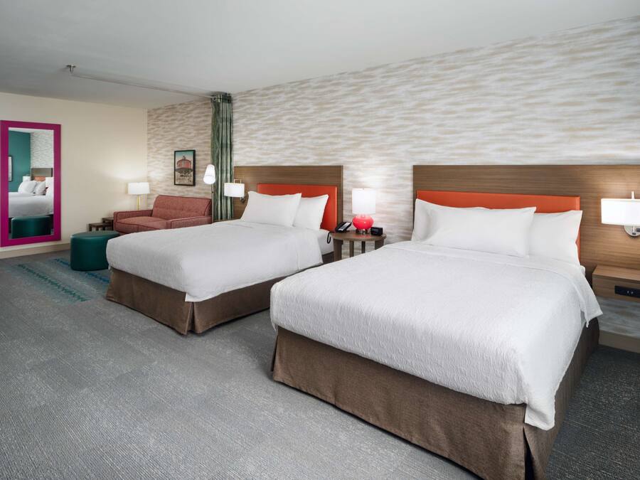 Une chambre d’hôtel avec deux lits, un canapé, un miroir et une petite table.