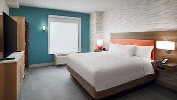 A hotel room with a bed, a television, a desk, and a window.