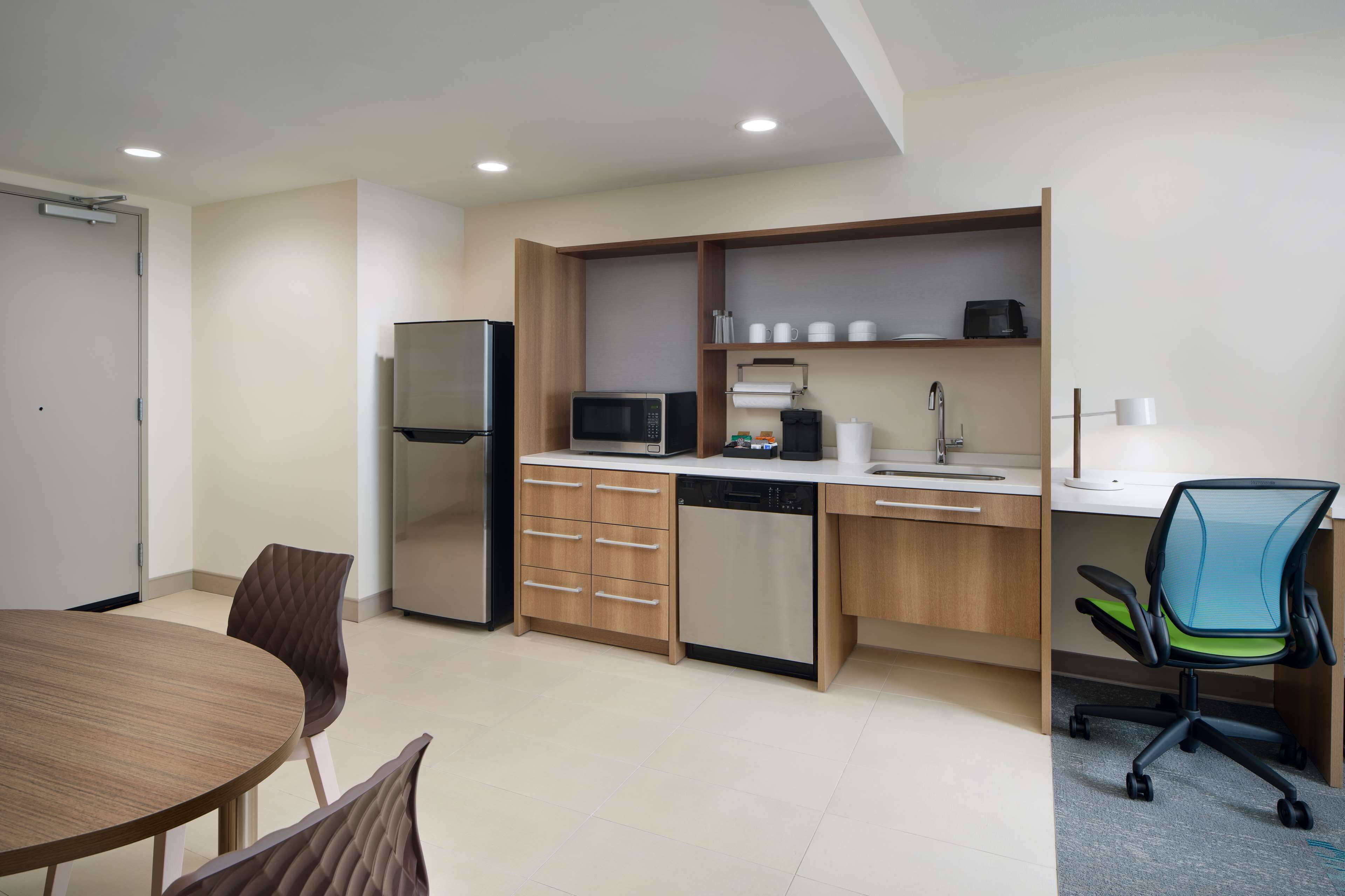 Eine moderne Küche mit Kühlschrank, Mikrowelle, Geschirrspüler und einem Essbereich mit Tisch und Stühlen.