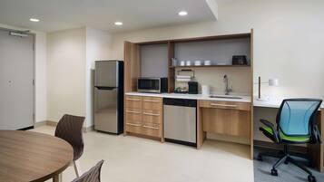 A modern kitchen with a refrigerator, microwave, dishwasher, and a dining area with a table and chairs.