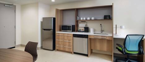 Eine moderne Küche mit Kühlschrank, Mikrowelle, Geschirrspüler und einem Essbereich mit Tisch und Stühlen.