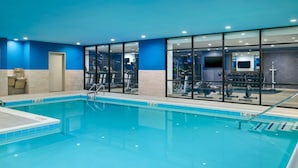 An indoor swimming pool with clear lane markings, a changing room, and exercise equipment visible through the glass walls. - Home2 Suites by Hilton Towson (Towson)
