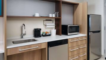A modern kitchen with a stainless steel sink, a coffee maker, a microwave, and a refrigerator.
