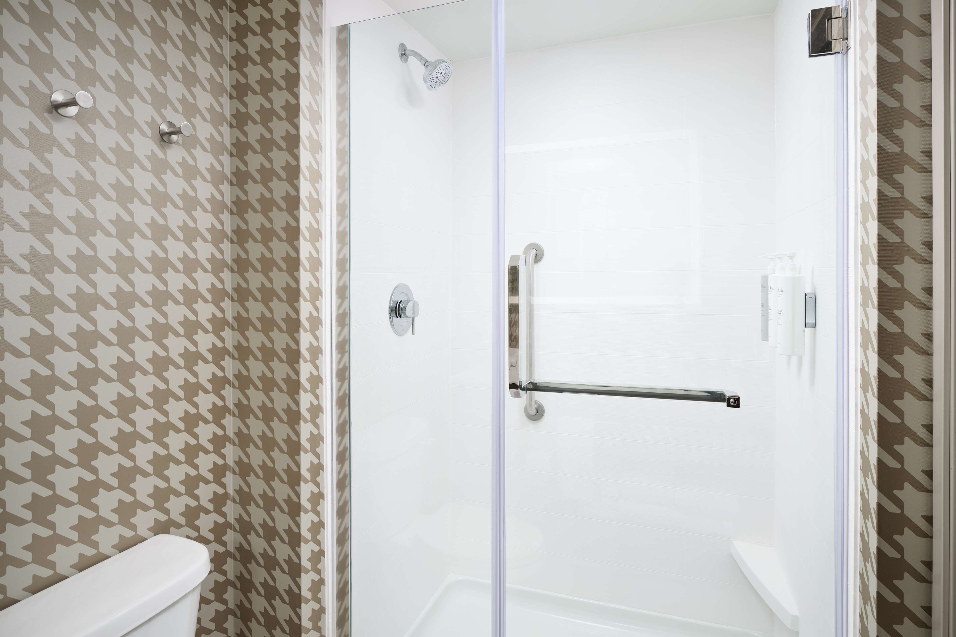 A bathroom with a shower, toilet, and patterned wall.
